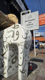 Bali Street Scene with Arabic Calligraphy Sculpture and Restaurant Sign