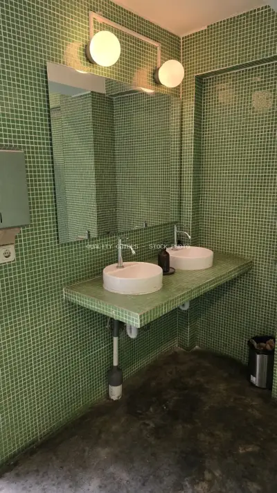 Modern Green Tiled Public Restroom with Double Sinks in Bali - stock photo