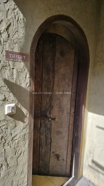 Rustic Wooden Toilet Door with Arched Frame in Bali - stock photo
