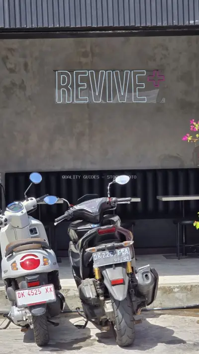 Modern "REVIVE +" Neon Sign with Scooters in Canggu, Bali - stock photo