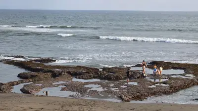 People Exploring Rocky Tide Pools on Seseh Beach, Bali - stock photo