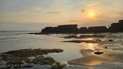 Golden Sunset over Cemagi Beach, Bali with Rocky Coastline - stock photo