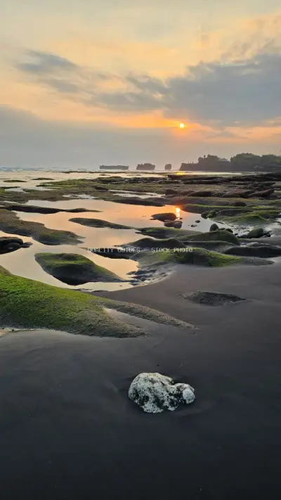Golden Sunset over Mengening Beach, Bali with Mossy Rocks - stock photo