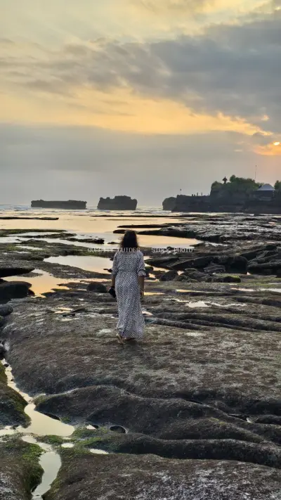 Woman Exploring Rocky Bali Beach at Golden Sunset - stock photo