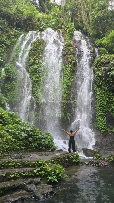 Woman with Arms Raised at Banyu Wana Amertha Waterfall Bali - stock photo