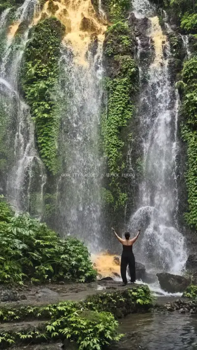 Woman with Arms Raised at Tropical Waterfall Bali - stock photo