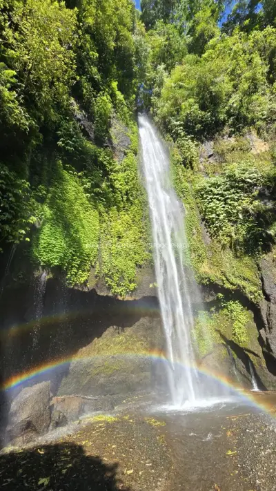 Tropical Waterfall with Rainbow Mist in Lush Jungle - stock photo