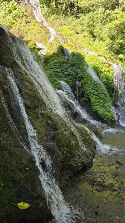 Cascading Waterfall Moss-Covered Rocks Bali Jungle - stock photo