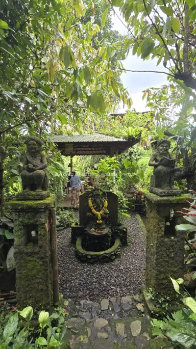 Balinese Temple Shrine with Stone Statues and Lush Greenery - stock photo