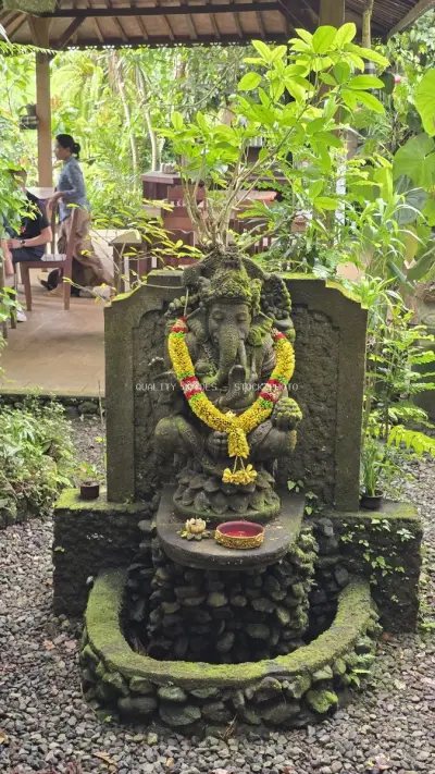 Ancient Ganesha Statue with Yellow Flower Garland Bali - stock photo