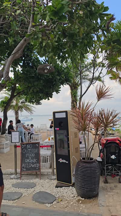 Vertical footage of a lively beachside restaurant and cafe in Sanur, Bali, with outdoor dining and tropical plants. - stock photo