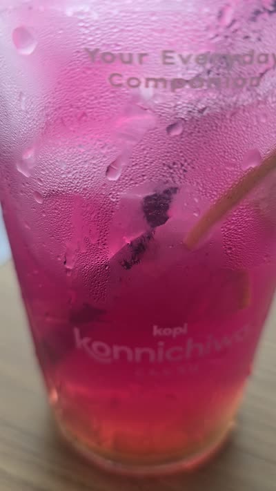 Pink iced drink on a table, panning up to reveal a modern cafe interior with staff and decorative shelves. - stock photo