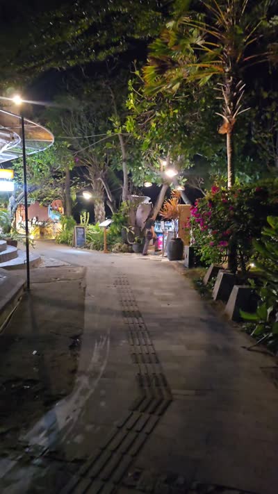 Nighttime footage of Stuja di Pantai cafe exterior in Bali, showing illuminated outdoor seating and tropical plants. - stock photo