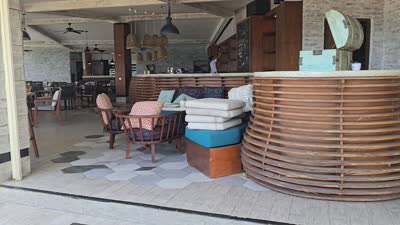 Beachfront restaurant interior panning to a sunny Bali beach with traditional boats and ocean view. - stock photo
