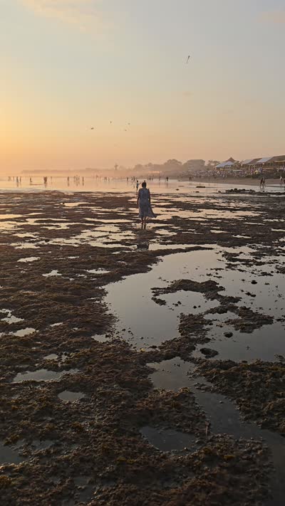 Sunset low tide at Mejan Stone Beach, Bali, with people walking on the exposed seabed. - stock photo