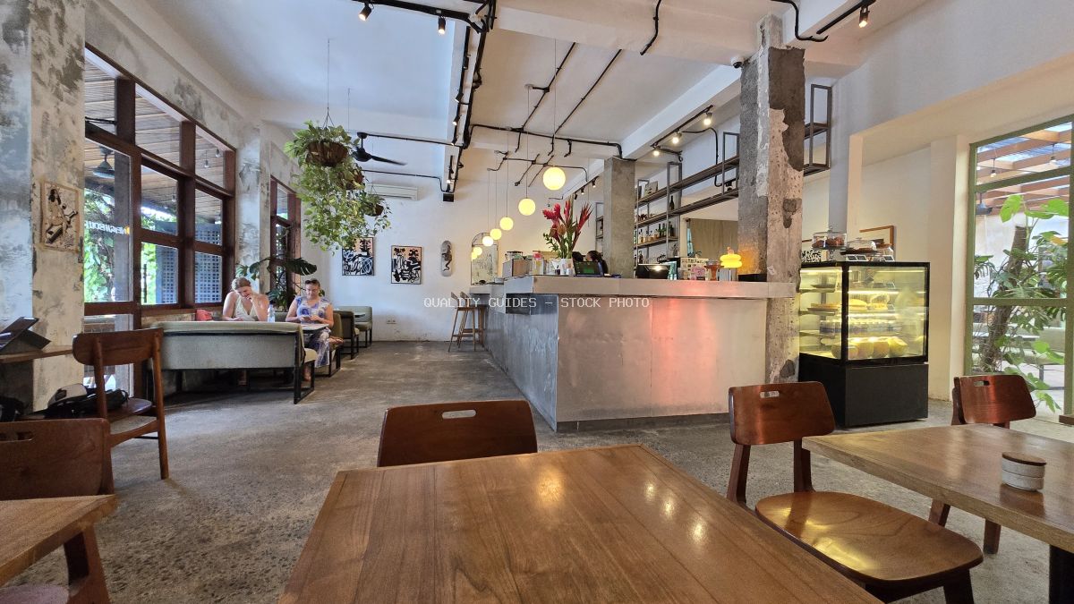 Interior of a modern industrial cafe with customers, wooden furniture, and a concrete bar. - stock photo