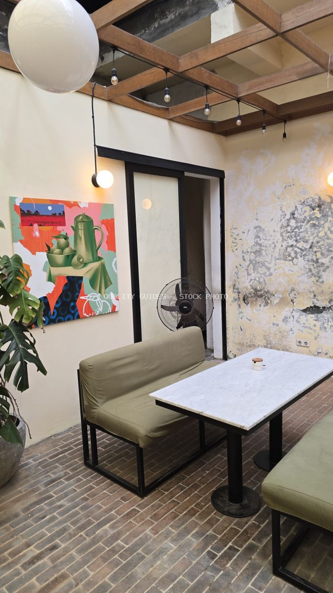 Interior of a modern cafe with green bench, marble table, brick floor, and colorful art. - stock photo