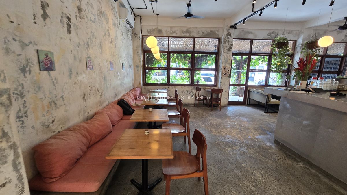 Interior of a modern cafe with rustic concrete walls, pink bench seating, wooden tables, and large windows. - stock photo