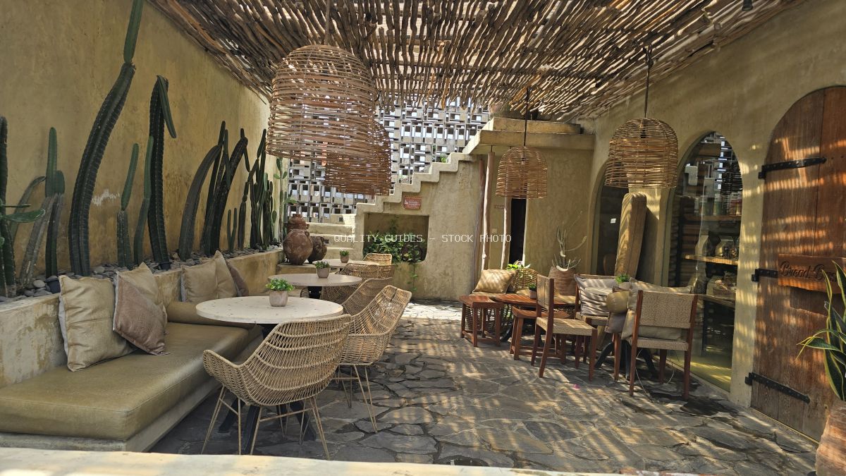 Rustic cafe interior with woven ceiling, stone floor, cacti, and wicker furniture in Bali. - stock photo