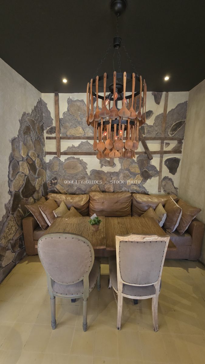 Rustic cafe interior with a unique wooden spoon chandelier, wooden table, leather sofa, and upholstered chairs. - stock photo