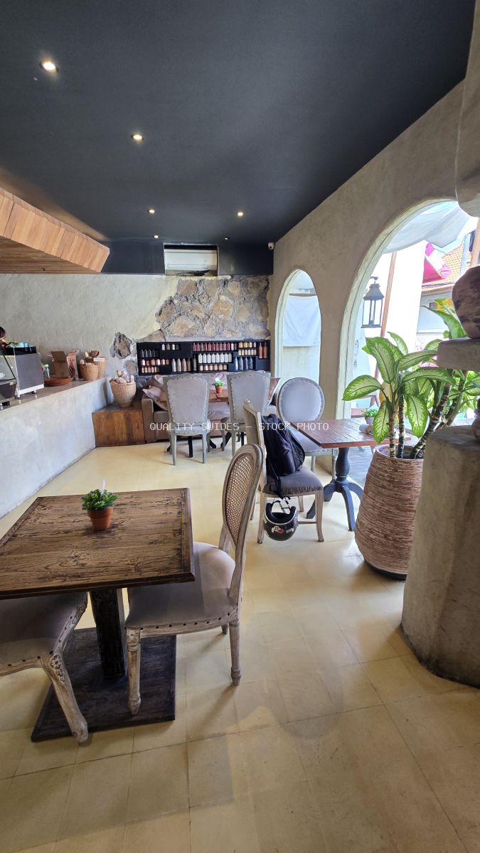 Interior of a rustic cafe in Bali with empty tables, stone walls, and arched doorways. - stock photo
