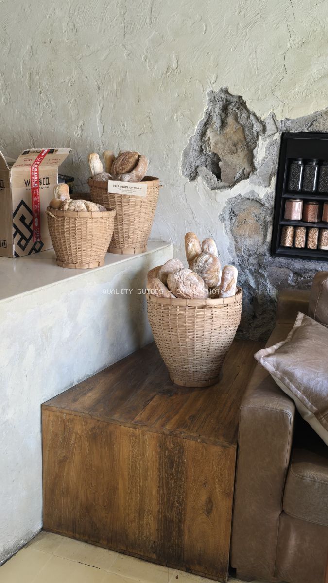 Wicker baskets filled with various breads on a wooden counter in a rustic bakery. - stock photo