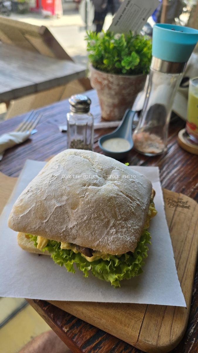 Ciabatta sandwich with lettuce on a wooden board at a cafe. - stock photo