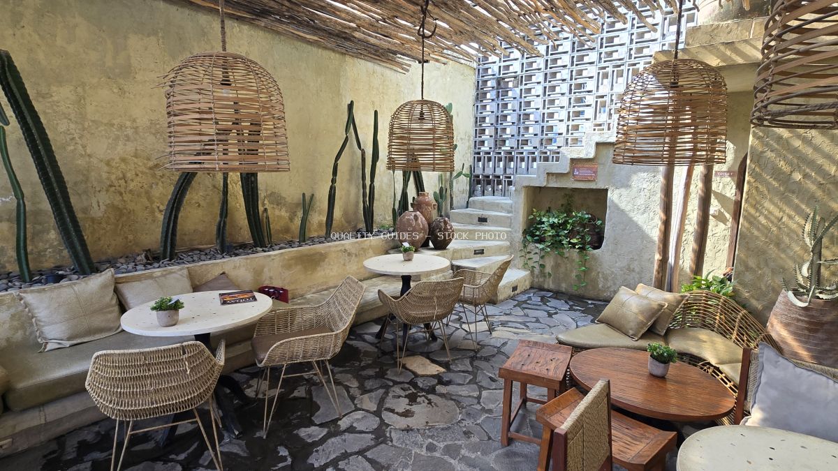 Outdoor cafe seating in Bali with wicker furniture, cacti, and rustic decor under natural light. - stock photo