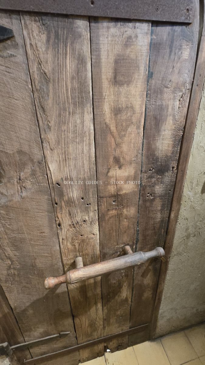Rustic wooden door with a rolling pin handle and weathered texture. - stock photo