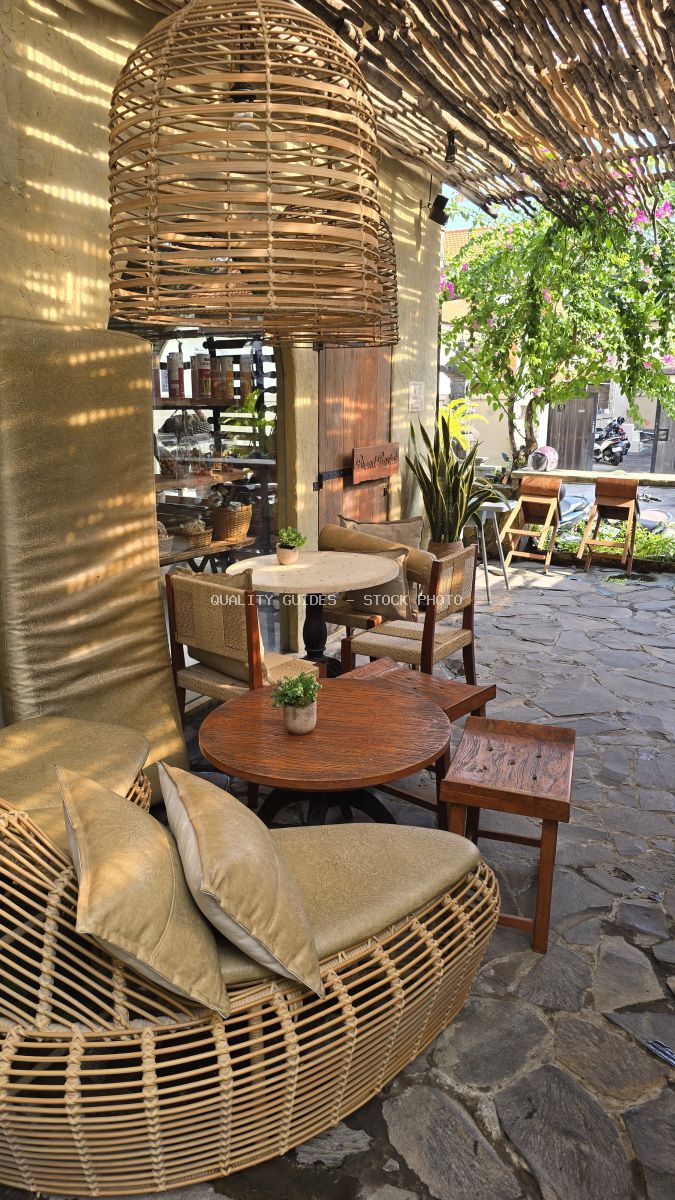 Outdoor cafe seating area with wicker chairs, wooden tables, and natural decor under a bamboo roof in Bali. - stock photo