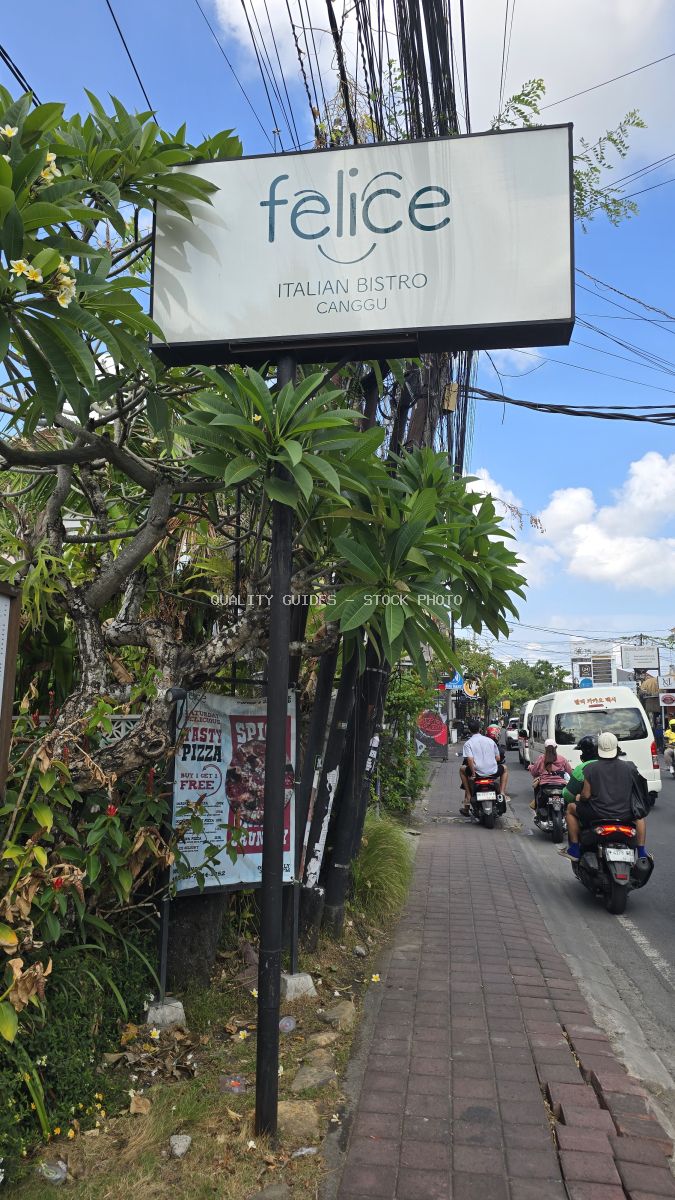 Sign for Felice Italian Bistro Canggu on a busy street with motorbikes in Bali. - stock photo