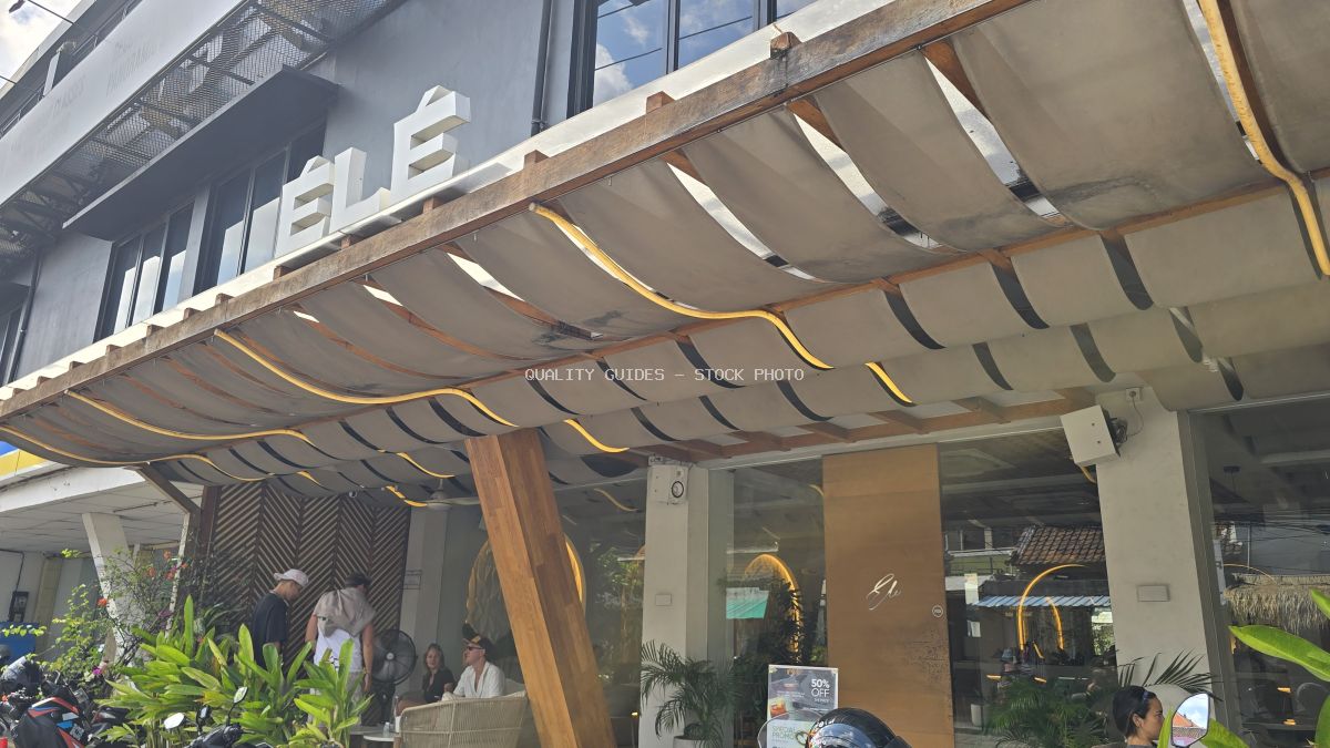 Exterior view of ÉLÉ Restaurant in Bali with a modern canopy, outdoor seating, and people. - stock photo