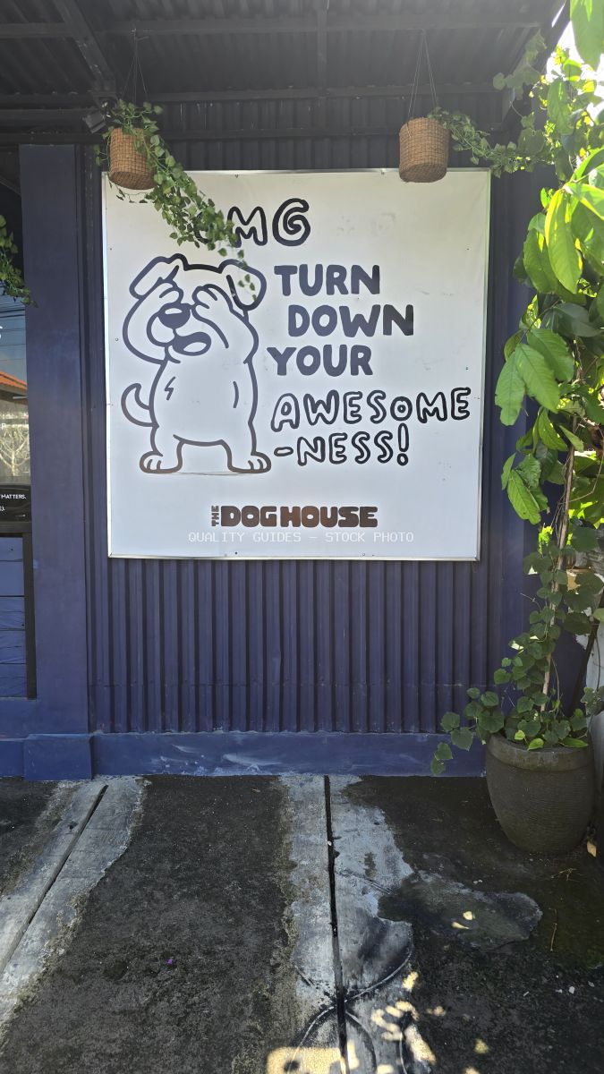 Exterior sign of The Dog House cafe in Bali with a cartoon dog and humorous text. - stock photo