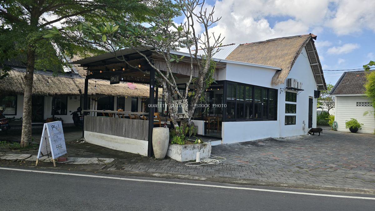 Exterior view of Poul Coffee Pastry cafe in Bali with thatched roof, modern windows, and a small pig. - stock photo