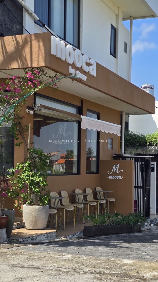 Exterior of Mooca by Susse coffee shop in Bali with brown facade, outdoor seating, and plants under a blue sky. - stock photo