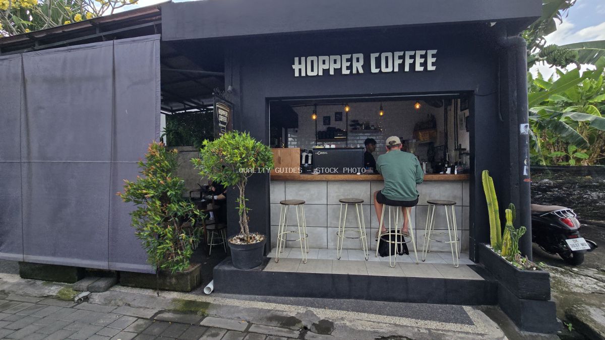 Exterior of Hopper Coffee in Bali with a customer at the counter and tropical plants. - stock photo