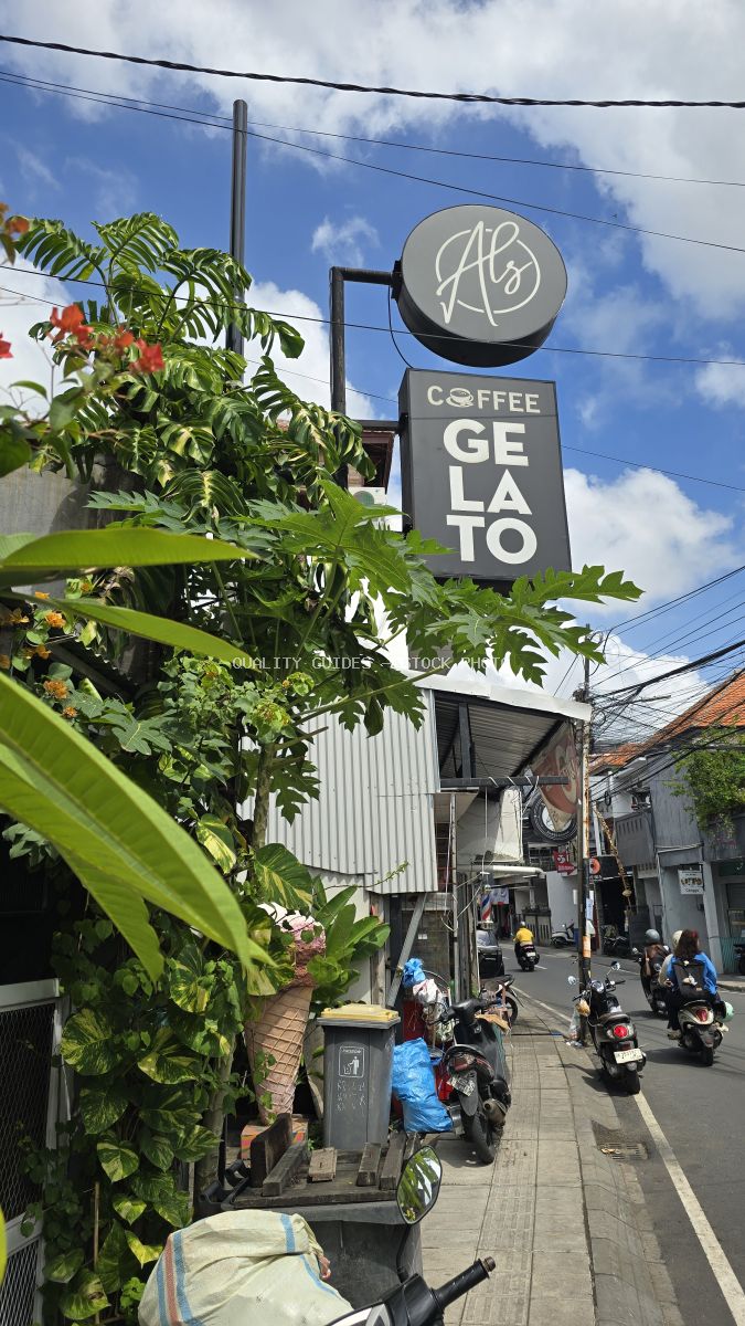 Street view of Al's Coffee & Gelato sign in Canggu, Bali, with tropical plants and motorbikes. - stock photo