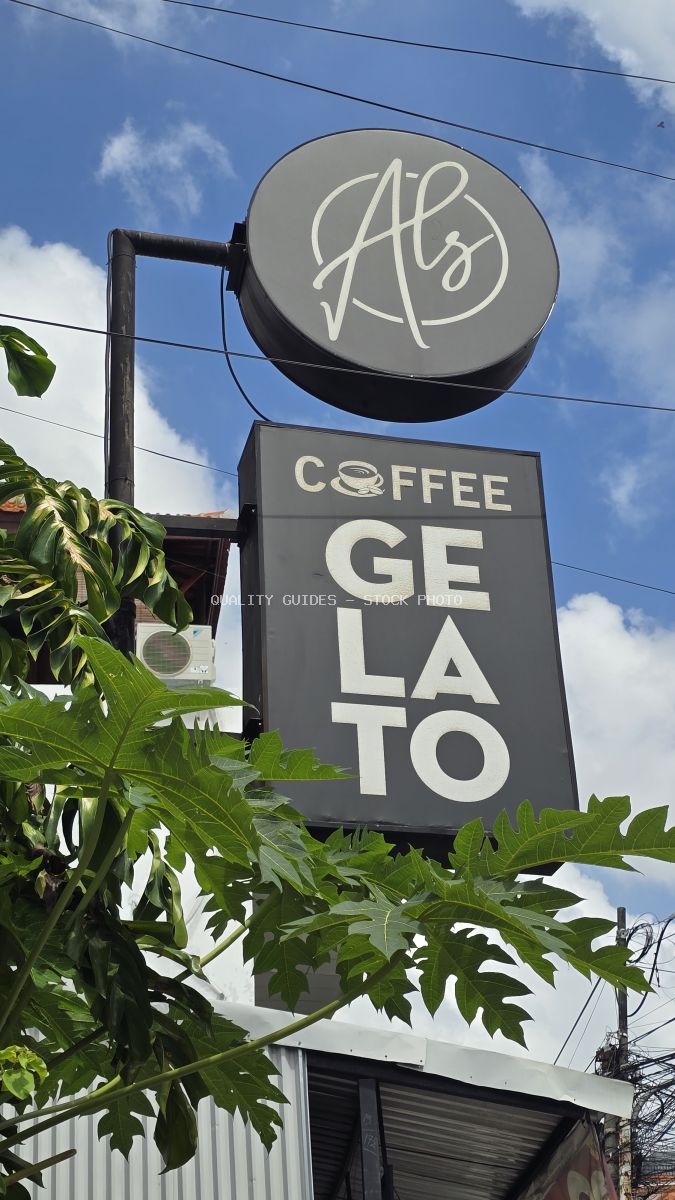 Al's Coffee Gelato sign in Canggu, Bali, with green tropical leaves and blue sky. - stock photo