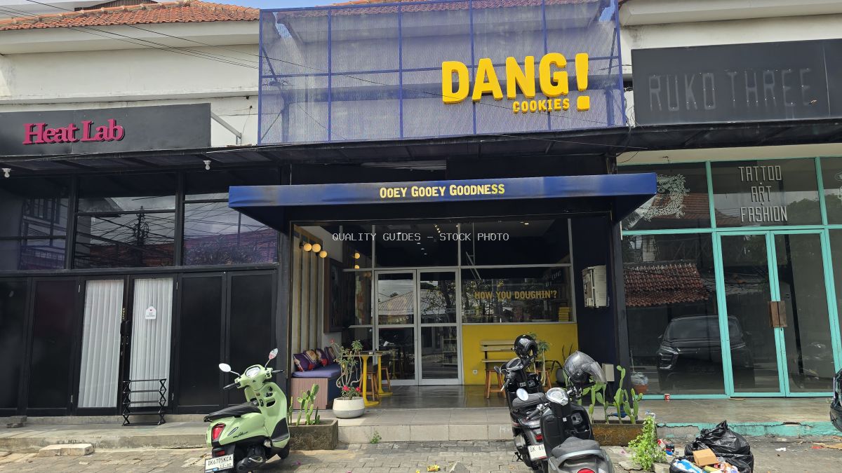 Exterior of Dang! Cookies shop in Bali with yellow sign, blue awning, and parked scooters. - stock photo