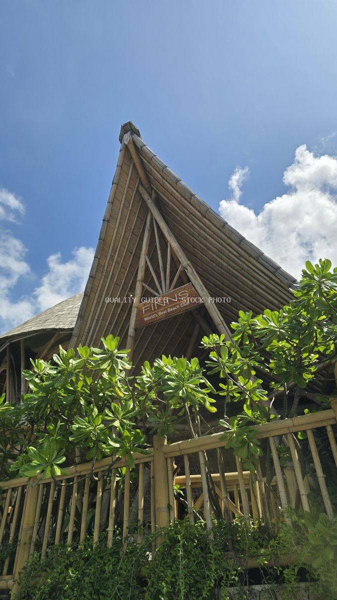 Finns Beach Club Bali bamboo roof and sign against a blue sky. - stock photo
