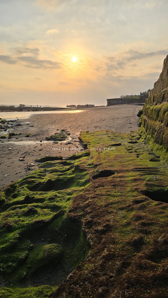 Sunset at Cemagi Beach, Bali, with mossy rocks and a sandy shore. - stock photo