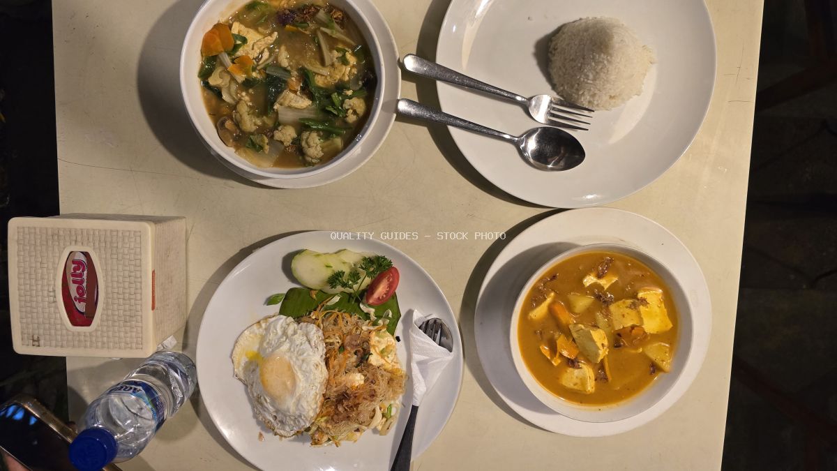Overhead view of Indonesian food on a table, including Nasi Goreng, vegetable soup, and a tofu curry. - stock photo