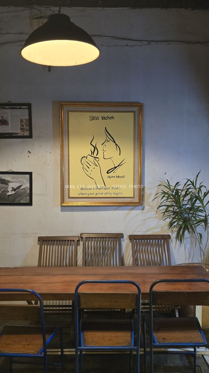 Interior of Sima Kitchen cafe with wooden table, chairs, and framed artwork on the wall. - stock photo