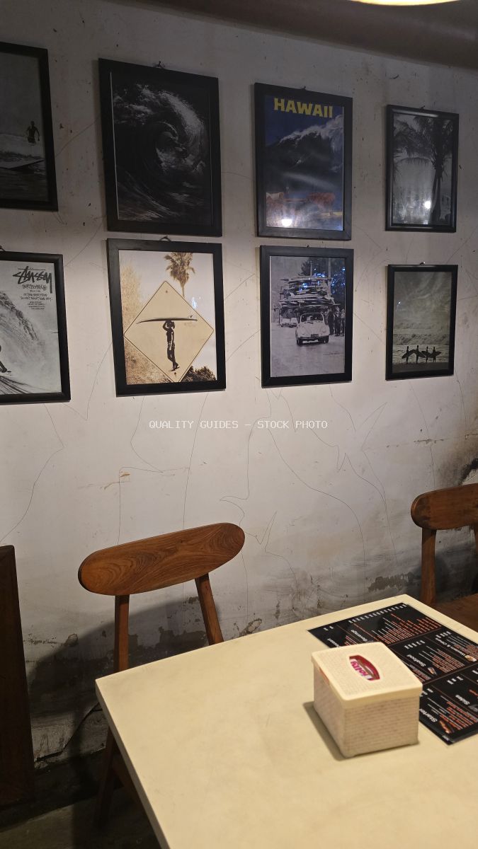 Interior of a Bali cafe with surf-themed wall art, wooden chairs, and a table with a menu. - stock photo