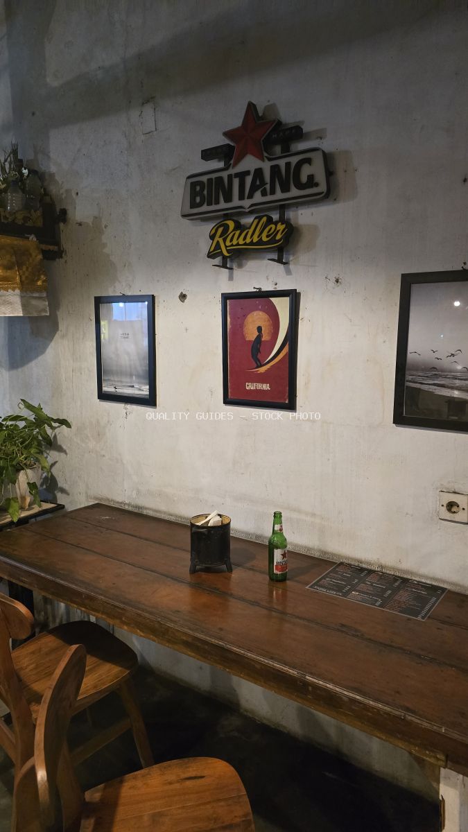 Interior of a rustic Bali bar with a Bintang Radler sign, wooden table, and chairs. - stock photo