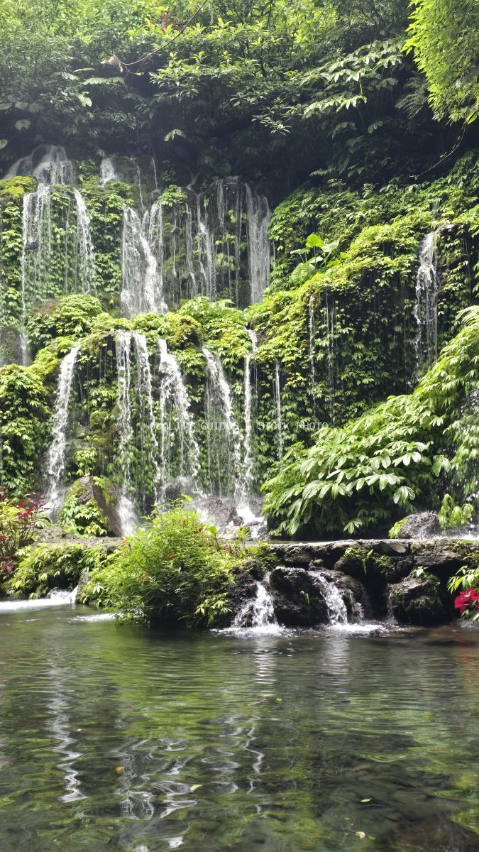 Multi-tiered waterfall in lush tropical forest with emerald pool, Banyu Wana Amertha Waterfall, Bali - stock photo