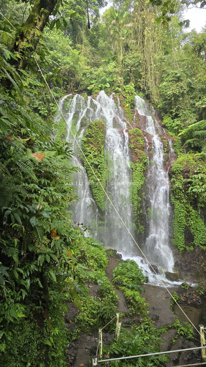 Banyu Wana Amertha Waterfall in Bali with cascading water through lush tropical jungle vegetation - stock photo
