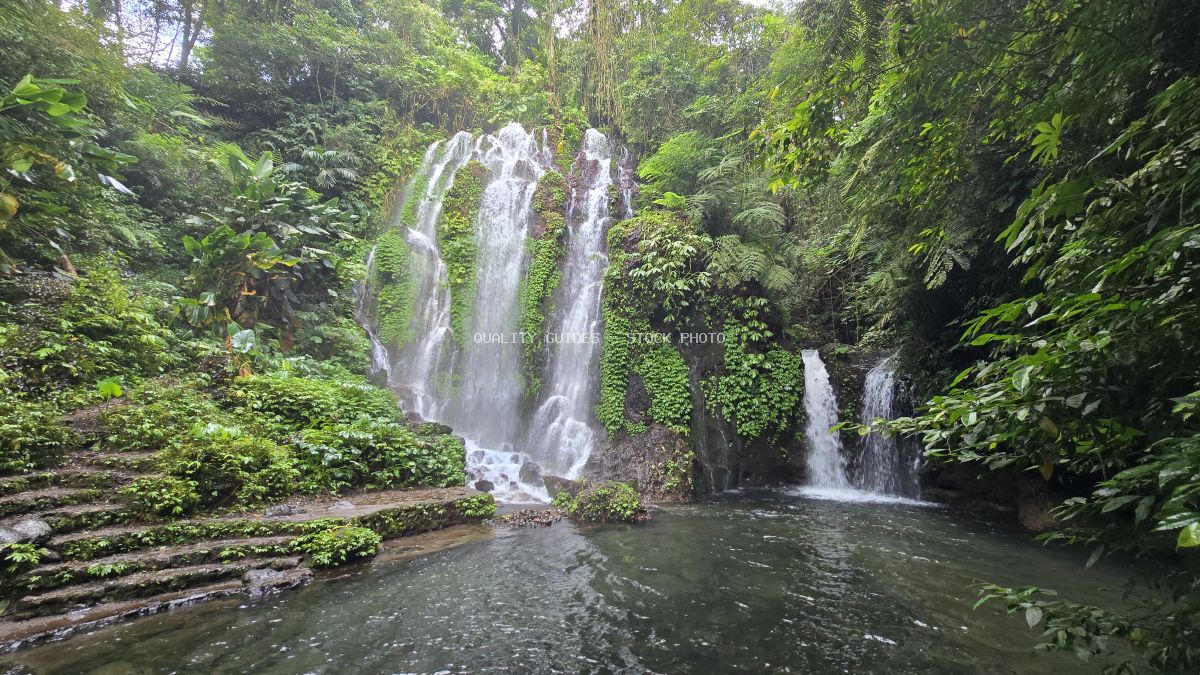 Banyu Wana Amertha Waterfall in Bali with cascading white water streams surrounded by lush tropical rainforest and emerald vegetation - stock photo