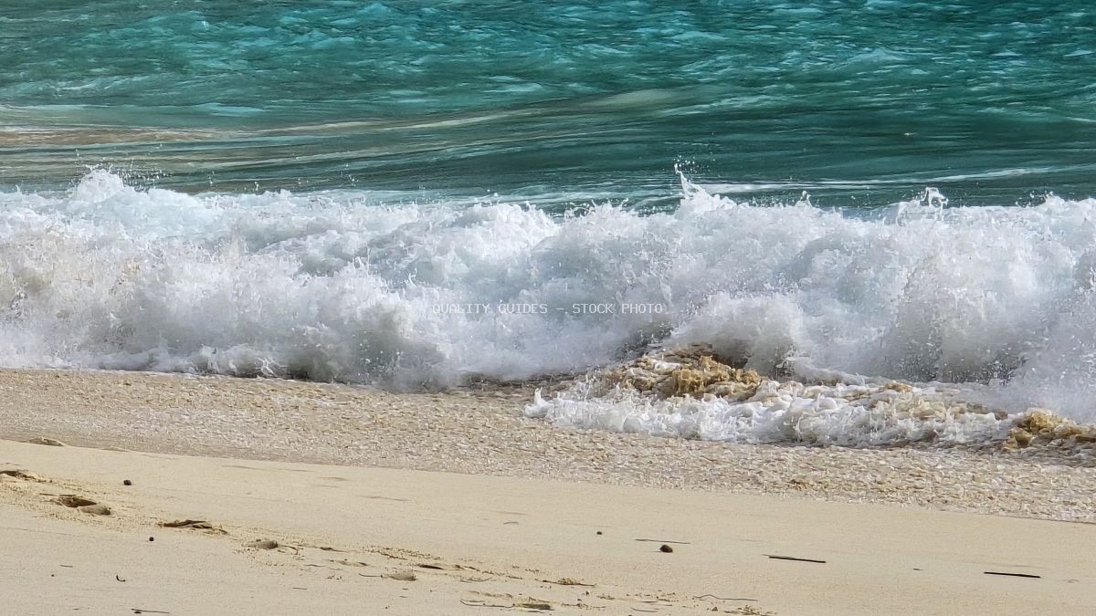 Turquoise ocean waves crashing on sandy Kelingking Beach in Bali with white foam and tropical waters - stock photo