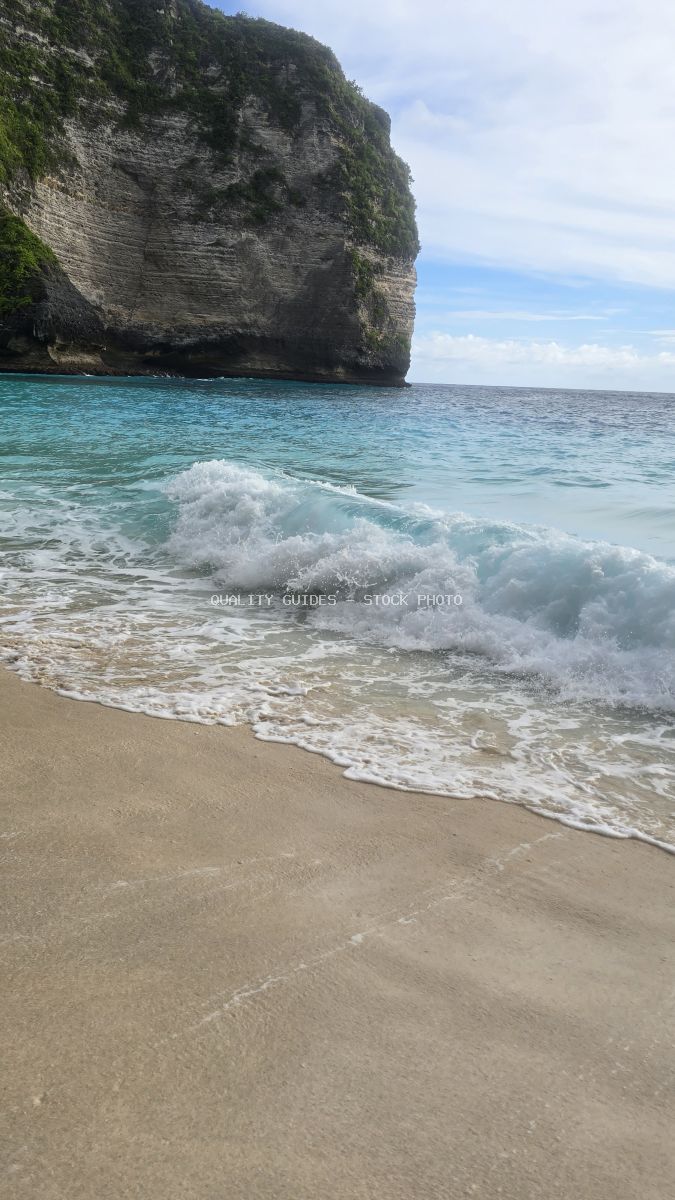 Dramatic limestone cliff with turquoise waves and white sand beach at Kelingking Beach, Bali - stock photo